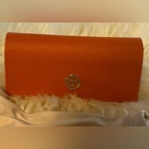 Orange Tory Burch hard eyeglass case with soft drawstring bag